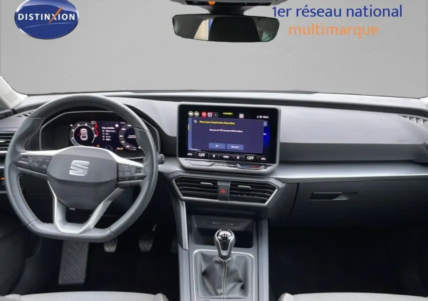 Vue intérieure frontale du tableau de bord et volant du SEAT LEON bleu Fjord, avec écran tactile et boîte manuelle.