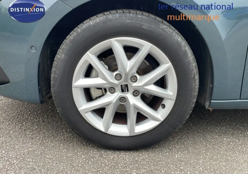 Gros plan sur la roue avant gauche d'une SEAT LEON 2.0 TDI 115CH STYLE XL bleu Fjord avec jante alliage argentée.