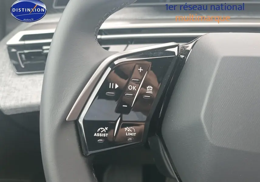 Gros plan sur les commandes au volant cuir du Peugeot 5008 gris Artense, avec tableau de bord en arrière-plan.