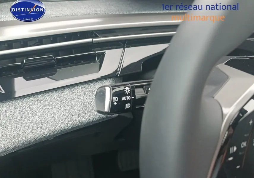 Détail du commodo d’éclairage à gauche du volant dans l’habitacle gris clair du Peugeot 5008 Hybrid 145 allure 2025.