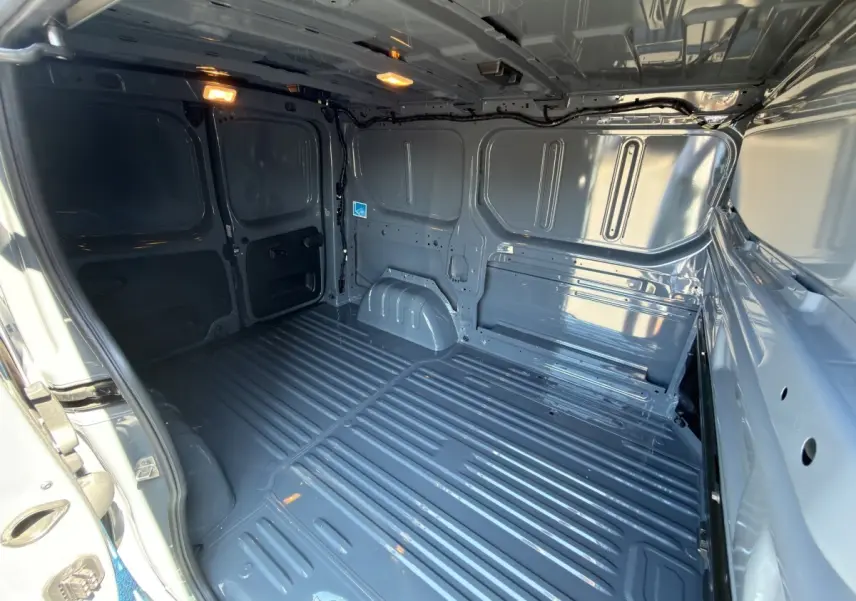 Vue intérieure arrière du fourgon Renault Trafic gris foncé, montrant l'espace de chargement vide et la cloison pleine.