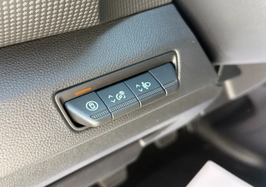 Gros plan sur les commandes de réglage des phares et verrouillage, tableau de bord noir du Renault Trafic gris foncé.