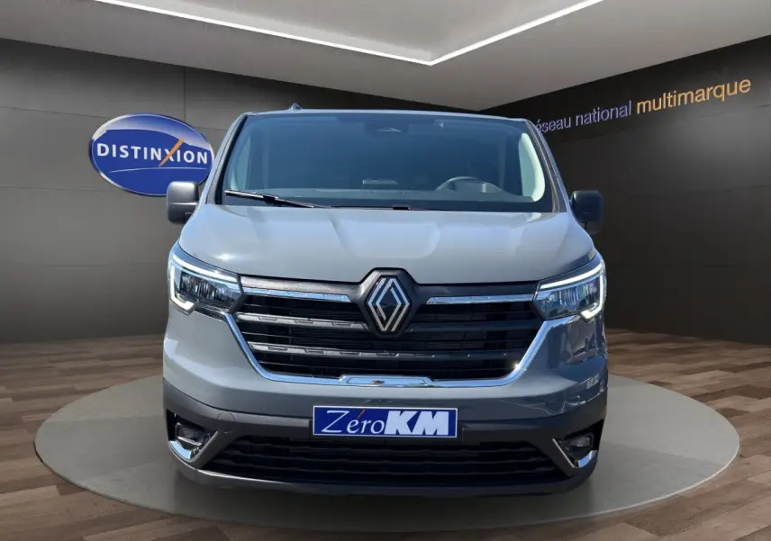 Vue avant d'un Renault Trafic Fourgon gris foncé avec calandre noire et phares LED allumés en showroom.