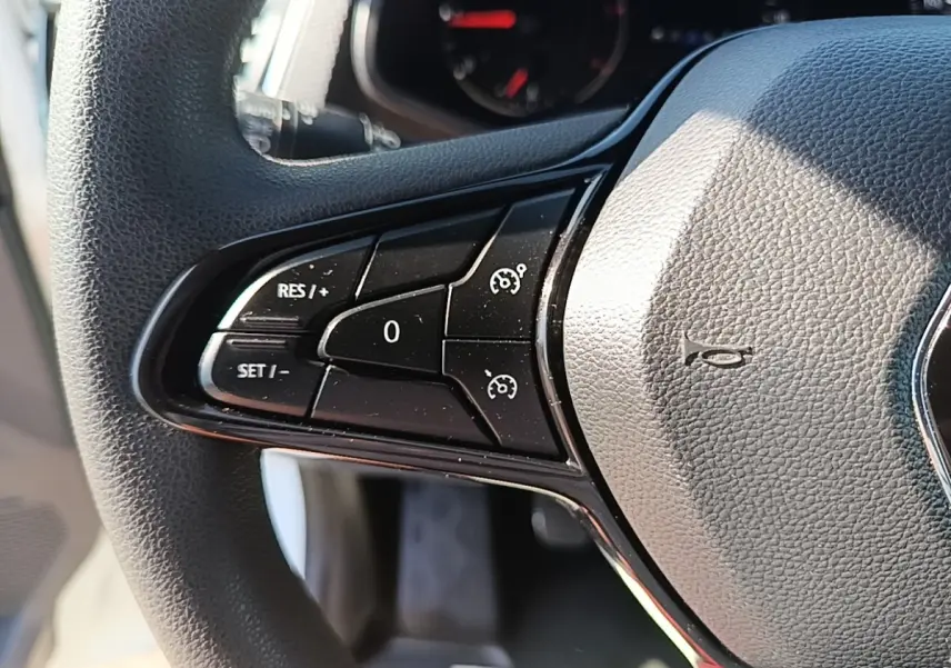 Gros plan sur le volant multifonctions noir du Renault Trafic Fourgon blanc, montrant les commandes de régulateur de vitesse.