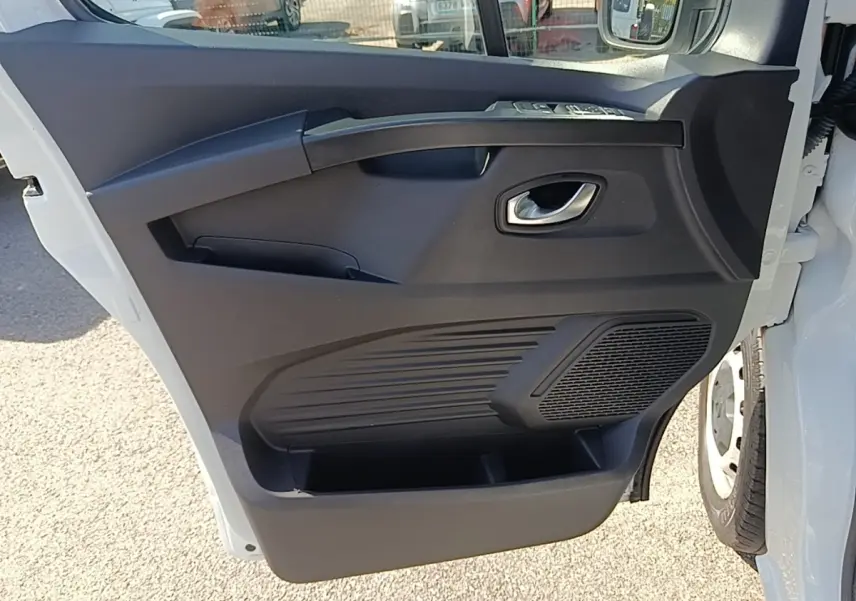 Vue rapprochée de la porte avant droite blanche du Renault Trafic Fourgon 2023 avec panneau intérieur noir et poignée argentée.