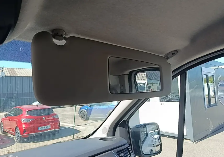 Vue intérieure du pare-soleil côté conducteur du Renault Trafic Fourgon blanc, avec rétroviseur et tableau de bord partiellement visibles.