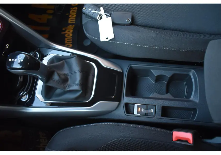 Vue rapprochée de la console centrale du Volkswagen T-Roc 2025 avec levier de vitesse DSG et sellerie tissu noire.
