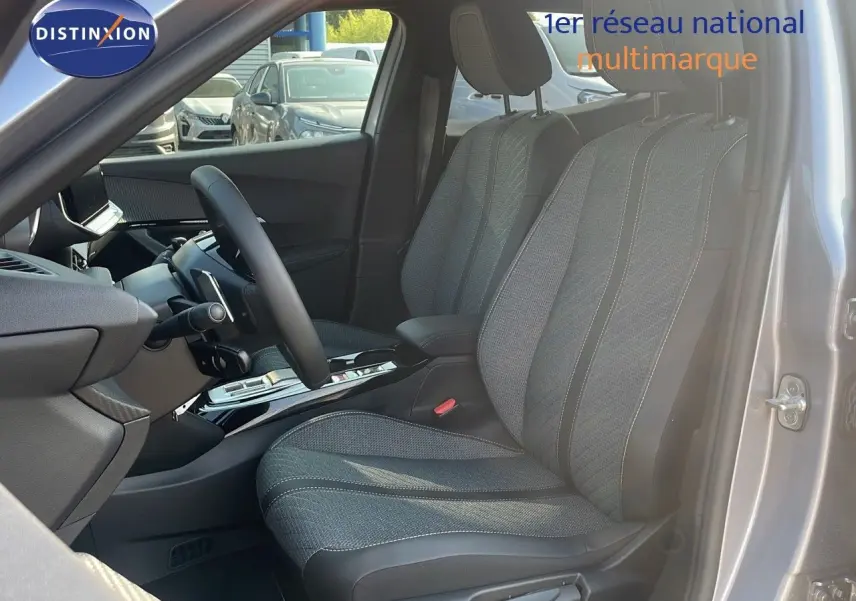 Vue intérieure côté conducteur du Peugeot 2008 gris Artense, mettant en valeur les sièges tissu et la console centrale moderne.