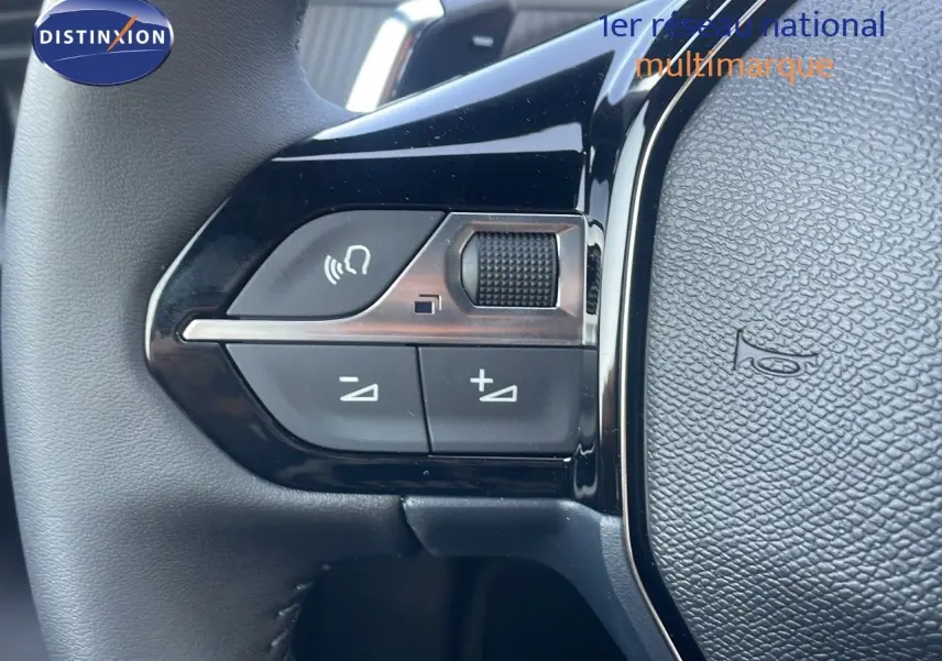 Gros plan sur les commandes du volant côté gauche du Peugeot 2008 gris Artense Hybrid 2025, boutons de volume et appel.