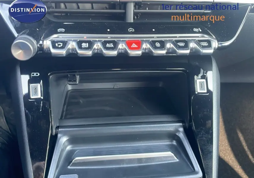 Gros plan sur la console centrale noire brillante du Peugeot 2008 Hybrid 136ch Allure avec boutons de commande et rangement ouvert.