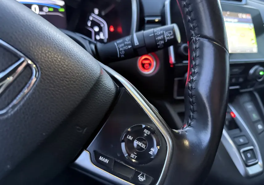 Gros plan sur le volant en cuir noir du Honda CR-V Hybrid 2019 avec commandes de régulateur de vitesse et tableau de bord lumineux.