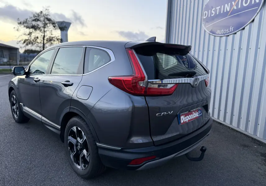 Vue 3/4 arrière droite d'un Honda CR-V gris 2019 avec feux arrière en forme de L et attelage visible.