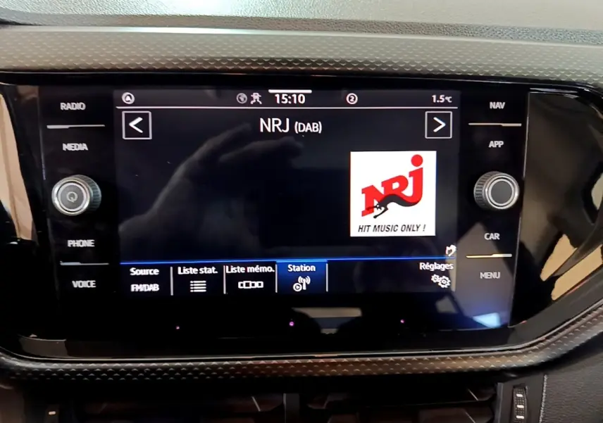 Écran tactile central du tableau de bord du Volkswagen T-Cross 2023 affichant la radio NRJ en mode DAB.