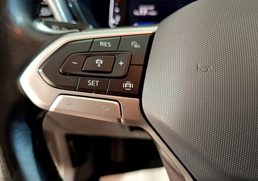 Gros plan sur le volant cuir multifonctions du Volkswagen T-Cross 2023, boutons de régulateur de vitesse visibles.