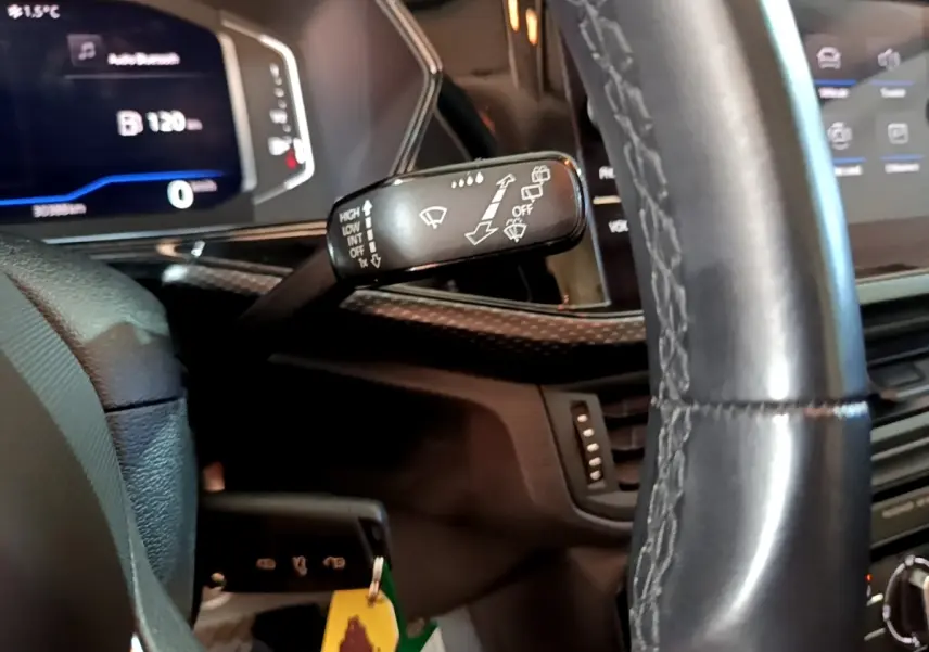 Gros plan sur le volant cuir et la commande d’essuie-glace du tableau de bord du Volkswagen T-Cross gris foncé 2023.