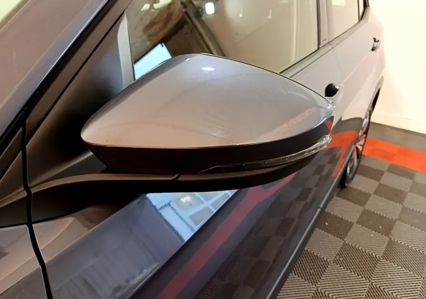Rétroviseur côté gauche gris foncé du Volkswagen T-Cross 2023, vue rapprochée avec carrosserie et partie latérale visibles.