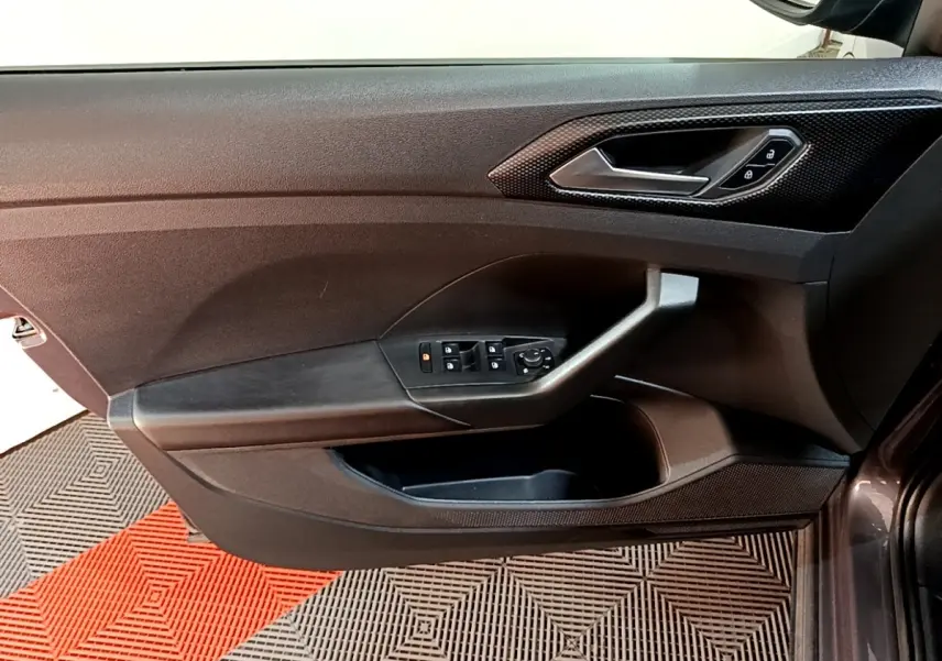 Vue rapprochée de la porte avant droite gris foncé du Volkswagen T-Cross 2023 avec commandes de vitres et verrouillage.
