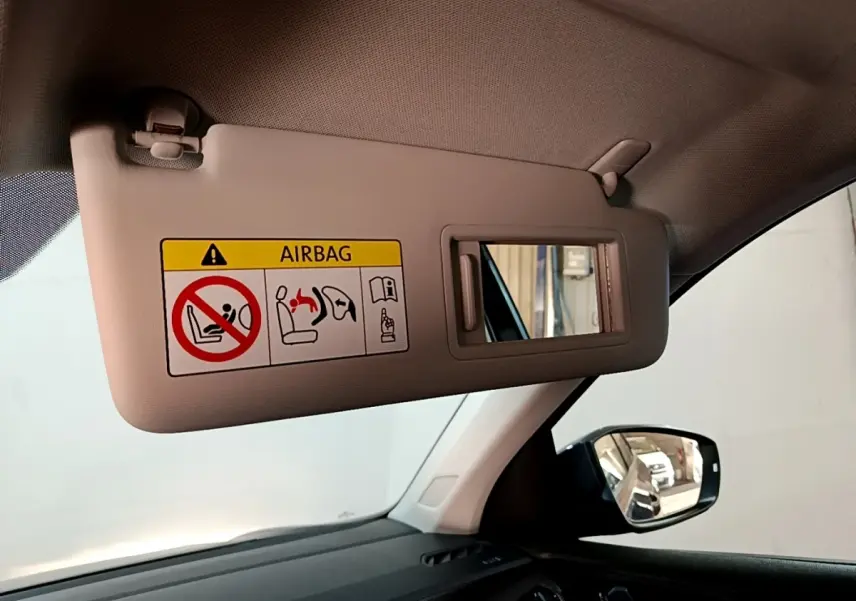 Vue intérieure côté gauche du pare-soleil beige avec miroir et avertissement airbag du Volkswagen T-Cross gris foncé 2023.