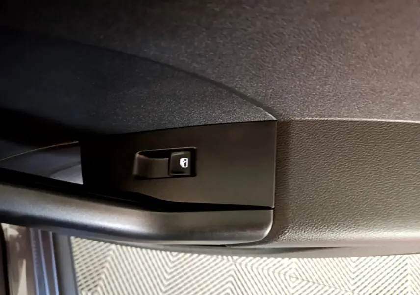 Détail de la poignée intérieure de porte côté gauche du Volkswagen T-Cross gris foncé, bouton de verrouillage visible.