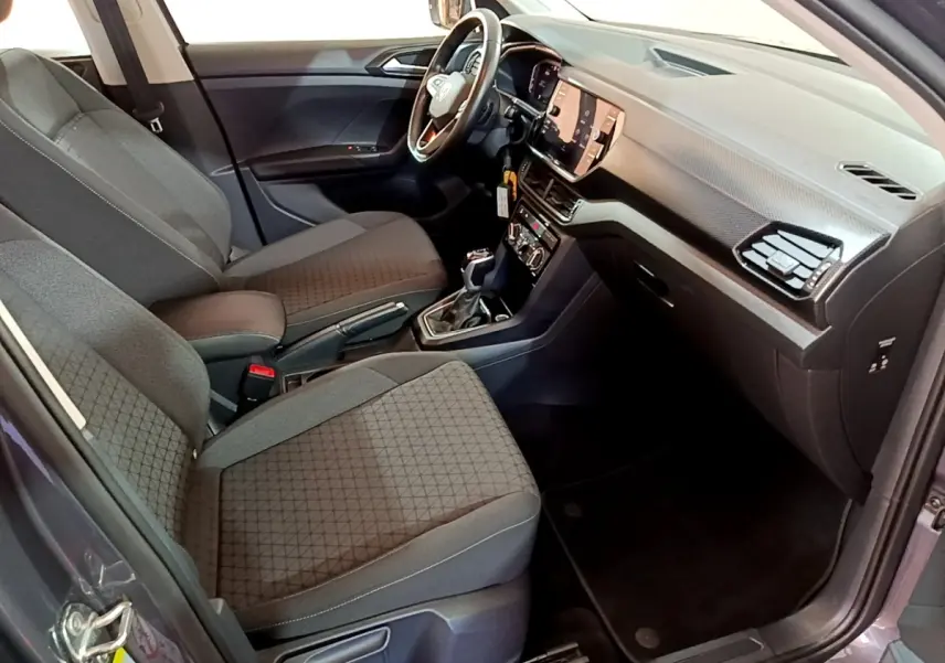 Vue intérieure côté conducteur du Volkswagen T-Cross gris foncé 2023, avec tableau de bord numérique et volant multifonctions cuir.