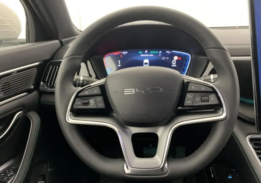 Vue rapprochée du volant noir en similicuir vegan du BYD SEAL U 2025 avec tableau de bord numérique lumineux.
