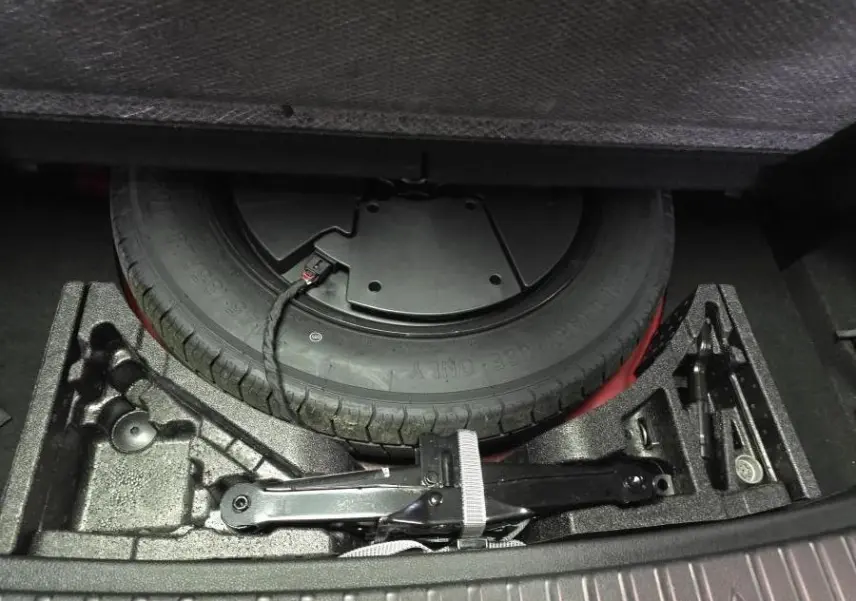 Vue rapprochée de la roue de secours et des outils de bord dans le coffre du Skoda Kodiaq rouge Sportline 2021.