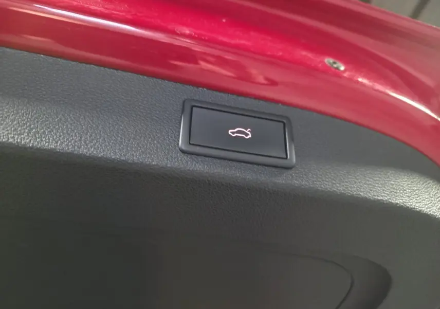 Bouton d'ouverture électrique du hayon sur la partie intérieure rouge du coffre d'un Skoda Kodiaq Sportline rouge.