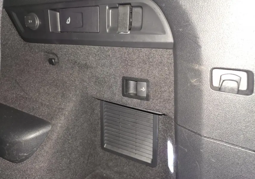 Détail intérieur du coffre du Skoda Kodiaq Sportline 2021, montrant les commandes de banquette rabattable et prise 12V.
