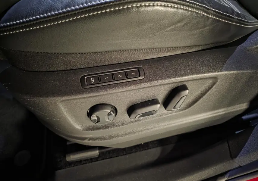 Gros plan sur les commandes de réglage électrique du siège conducteur en cuir noir du Skoda Kodiaq rouge.