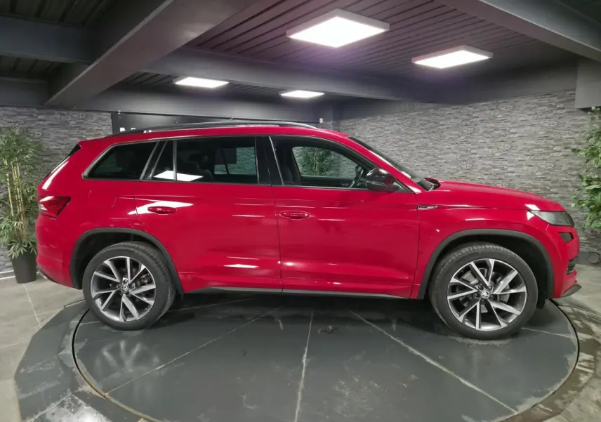 Vue latérale droite d'un SUV SKODA KODIAQ rouge 7 places avec jantes alliage 20 pouces dans un showroom.
