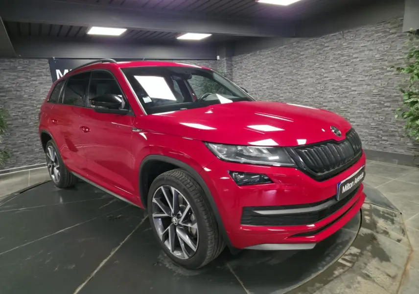 SKODA KODIAQ rouge en 3/4 avant droit, avec jantes alliage anthracite et calandre noire sportive.