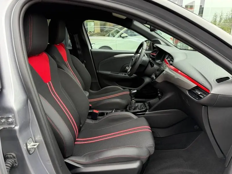 Vue intérieure côté conducteur de l'Opel Corsa 2023 avec sièges sport noirs et rouges et tableau de bord gris et rouge.