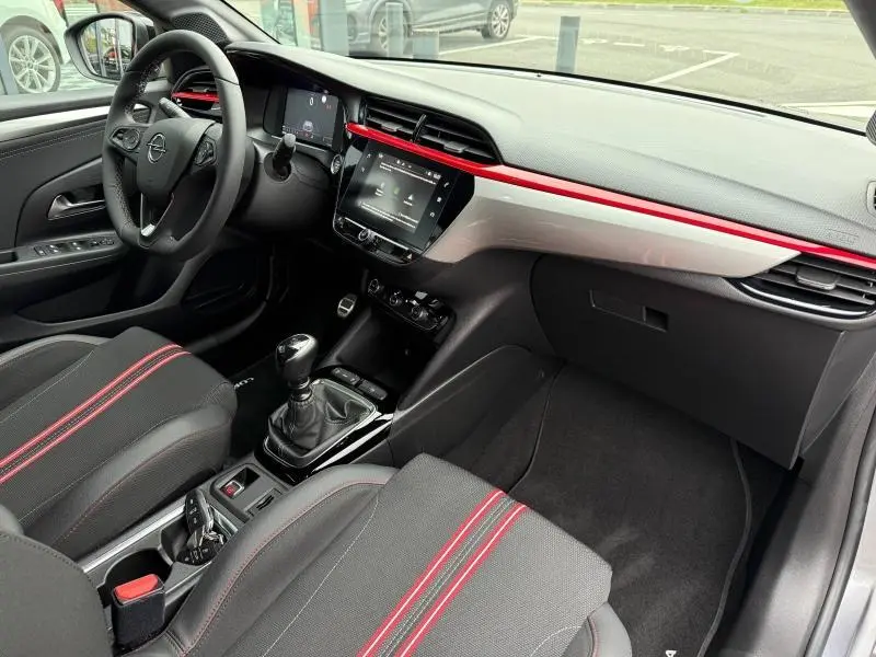 Intérieur avant droit de l’Opel Corsa 1.2 Turbo 2023 avec sièges noirs à surpiqûres rouges et tableau de bord noir et rouge.