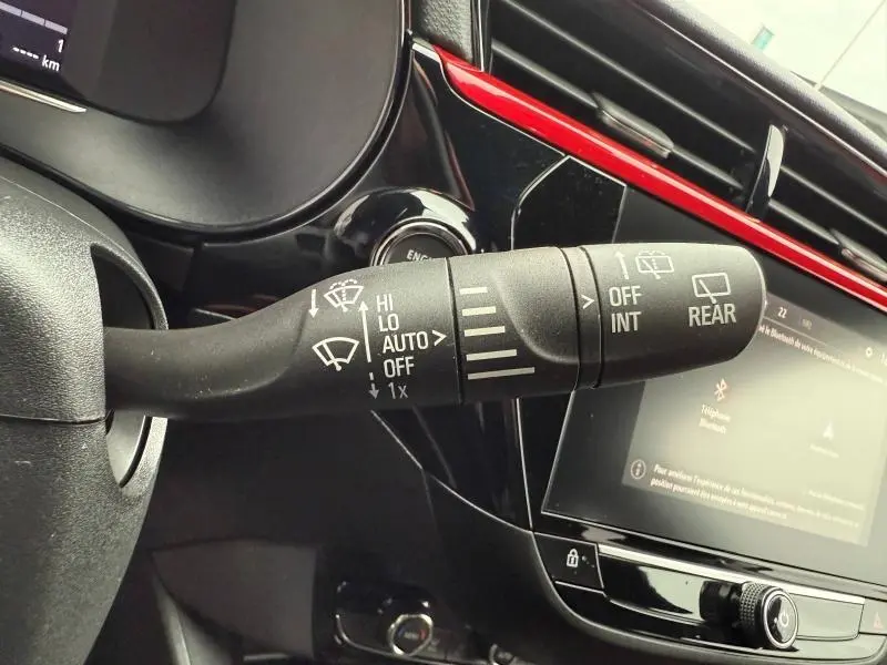 Gros plan sur la commande des essuie-glaces dans l’habitacle noir et rouge de l’Opel Corsa 2023.