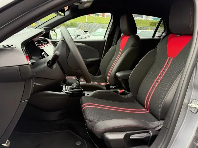 Vue intérieure côté conducteur de l’Opel Corsa 1.2 Turbo 2023, sièges sport noirs avec surpiqûres rouges et volant cuir.