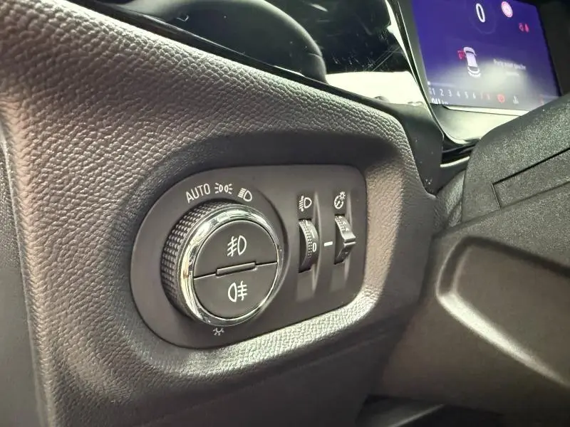 Gros plan sur les commandes d’éclairage noires et chromées du tableau de bord de l’Opel Corsa 2023.