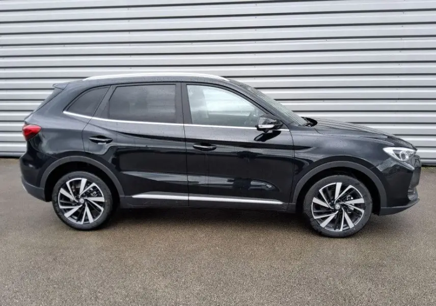 Vue de profil côté gauche du SUV MG ZS 1.5 Hybrid+ 197 Luxury en Pebble Black avec jantes alliage bicolores.