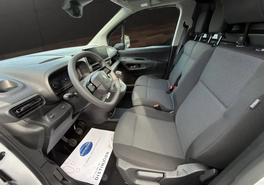 Intérieur avant du Citroën Berlingo blanc 2026, vue côté conducteur montrant les sièges 3 places et le tableau de bord moderne.