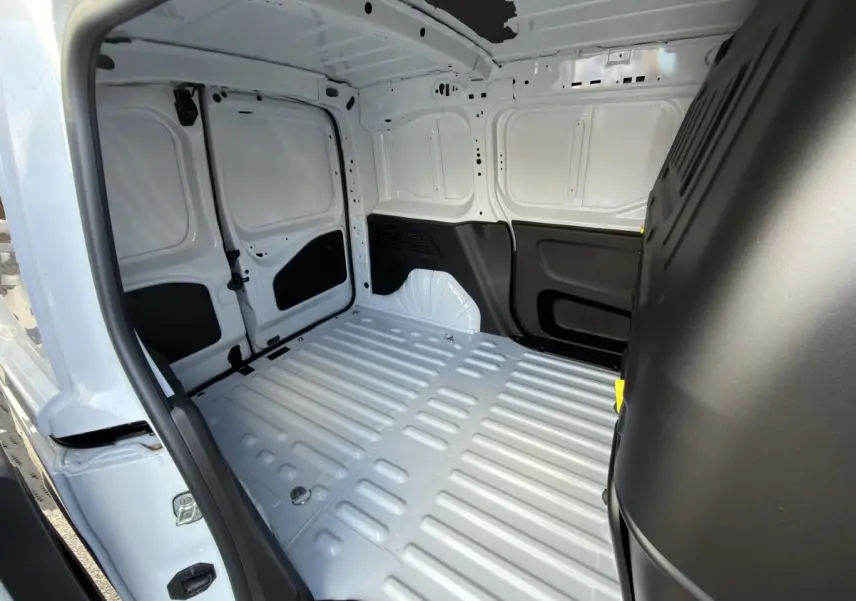Vue intérieure arrière du Citroën Berlingo blanc 2026, montrant l’espace de chargement vide et les parois métalliques.