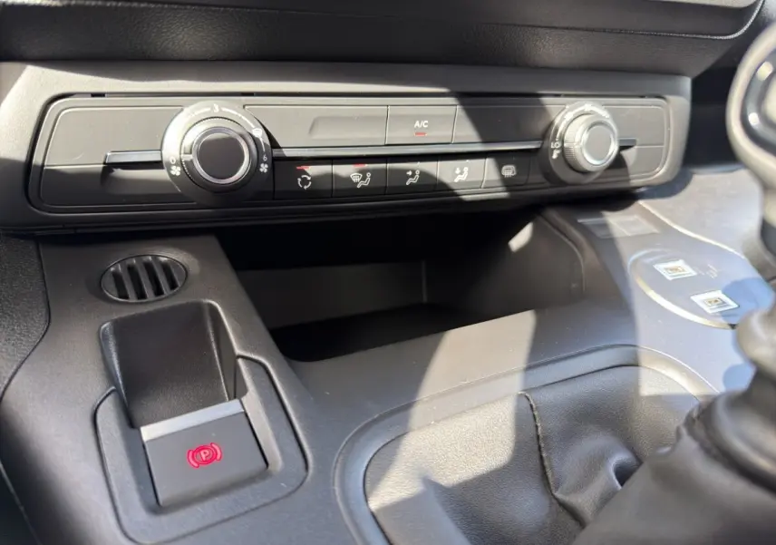 Gros plan sur la console centrale noire du Citroën Berlingo 2026, montrant les commandes de climatisation et frein électrique.