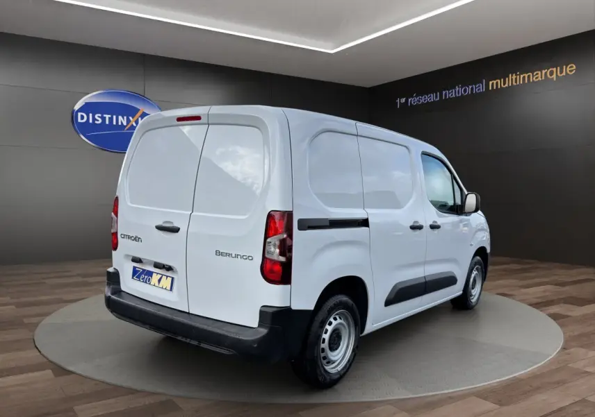 Vue 3/4 arrière droite d’un utilitaire Citroën Berlingo blanc avec portes arrière battantes et protections latérales noires.