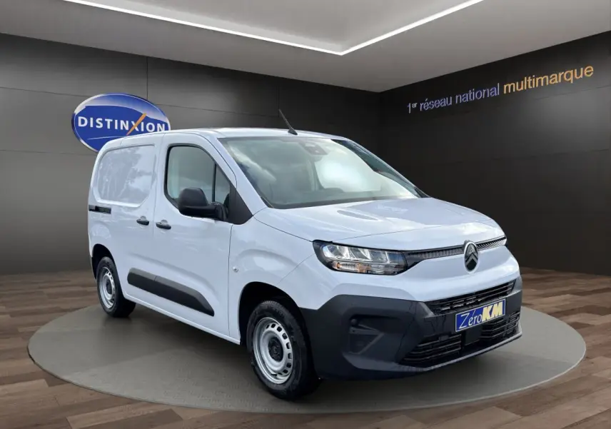 Vue 3/4 avant droit du Citroën Berlingo blanc avec pare-chocs noirs et jantes acier en showroom.