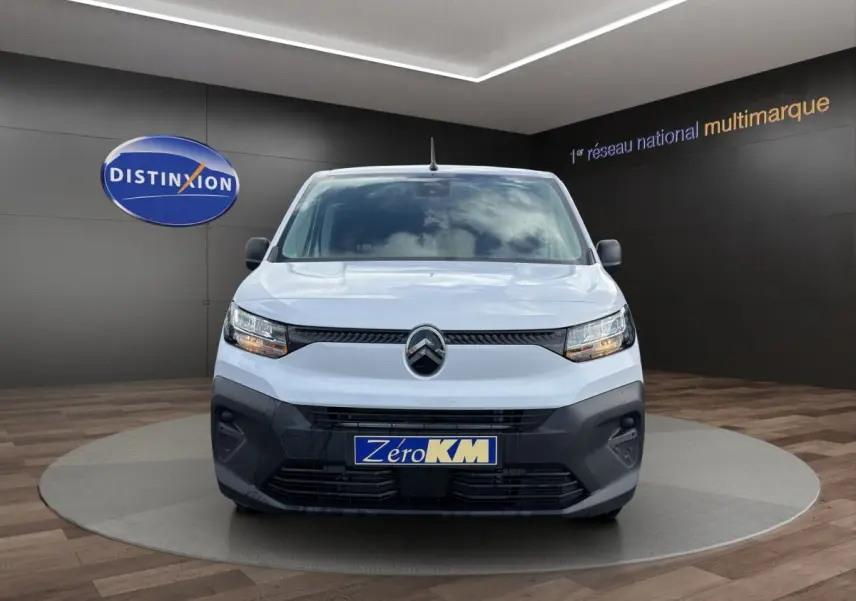 Vue avant d’un Citroën Berlingo blanc 2026 avec calandre noire et plaque Zéro KM en showroom.