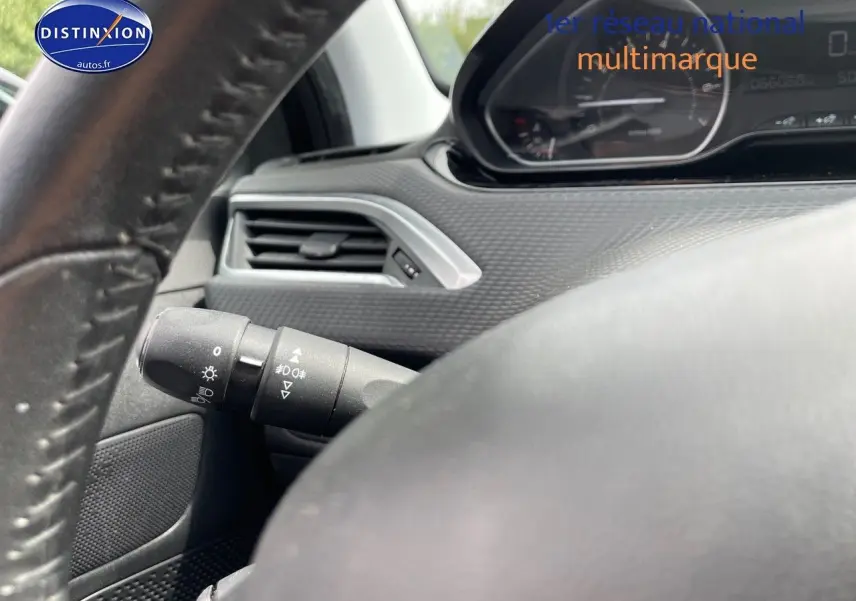 Gros plan sur le volant et la commande d'éclairage du tableau de bord d'une Peugeot 2008 noir métal, version 2016.