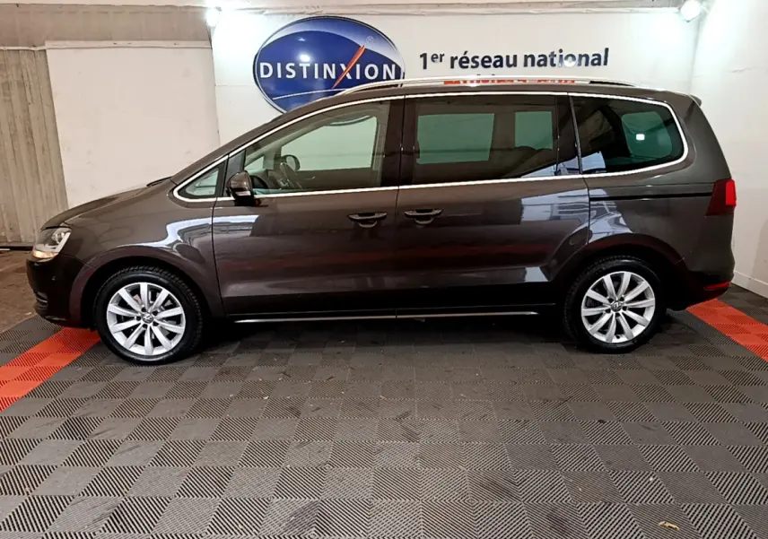 Vue de profil côté gauche d’un Volkswagen Sharan marron 2017, avec jantes alliage et vitres teintées, en intérieur showroom.