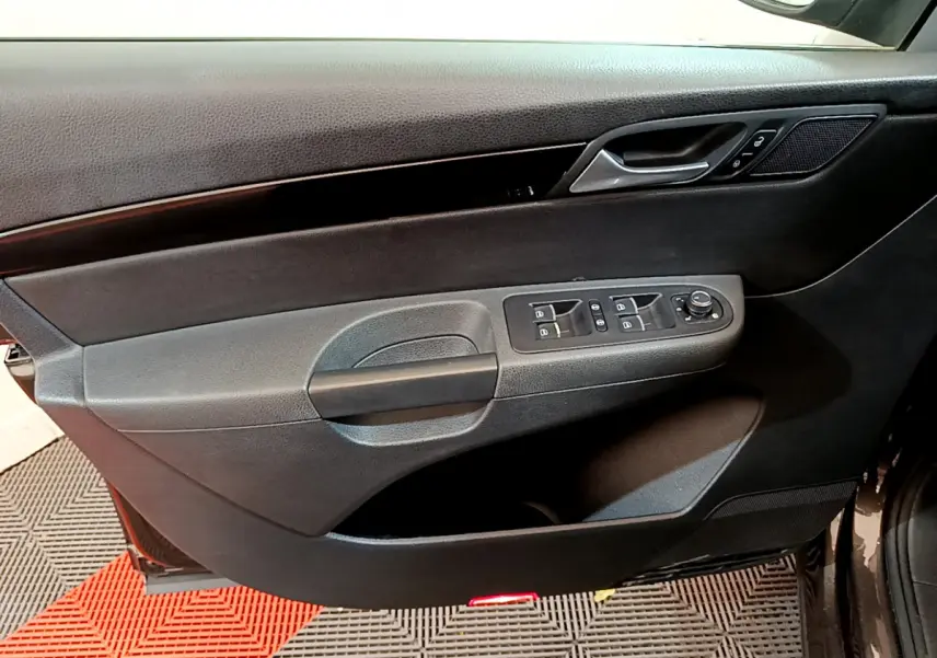 Vue rapprochée de la porte avant gauche noire du Volkswagen Sharan 2017 avec commandes électriques et poignée intégrée.