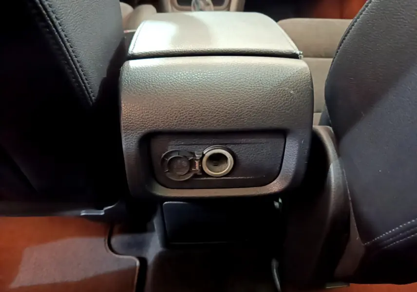 Prise 12V ouverte au dos de la console centrale, vue rapprochée de l'intérieur marron du Volkswagen Sharan 2017.