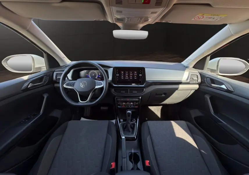 Vue intérieure avant du Volkswagen T-Cross 2025 avec tableau de bord noir et sièges tissu Life gris foncé.