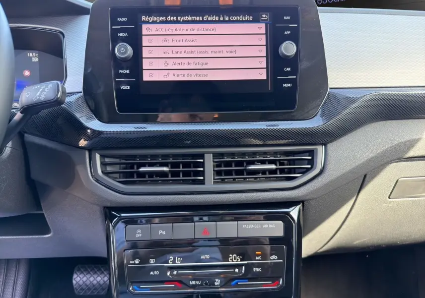Vue rapprochée du tableau de bord noir du Volkswagen T-Cross 2025, écran tactile affichant les aides à la conduite.
