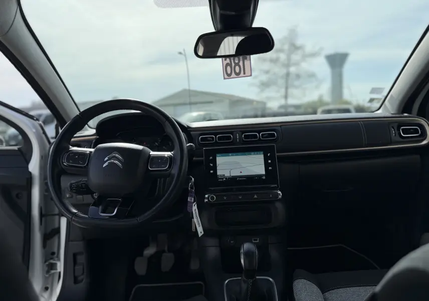 Vue intérieure avant de la Citroën C3 1.2 PureTech 83 Origins 2019, tableau de bord noir avec écran tactile et volant multifonctions.